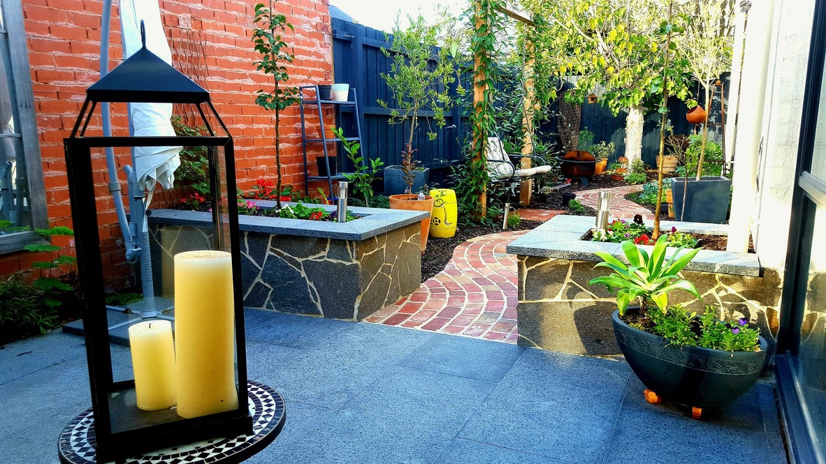 Completed courtyard entrance with stone planters and winding brick path