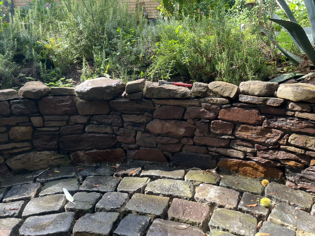 Pink mudstone retaining wall with curved bluestone paving